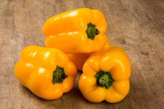 Sommige gele paprika's op een houten oppervlak. Verse groente.