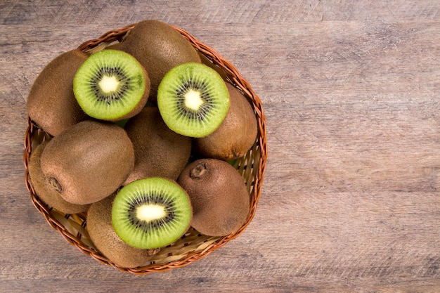 Sommige kiwi's in een mand op een houten oppervlak. Vers fruit