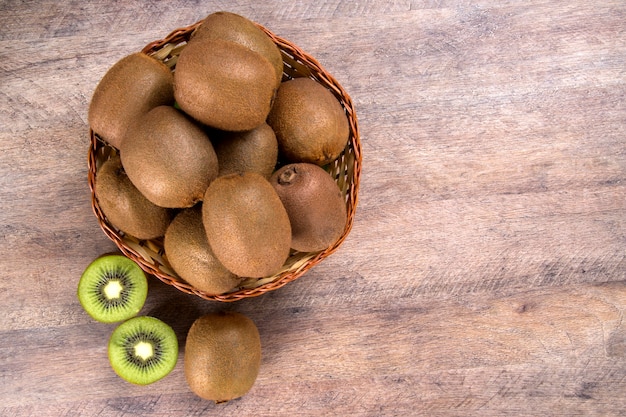 Sommige kiwi's in een mand op een houten oppervlak. Vers fruit