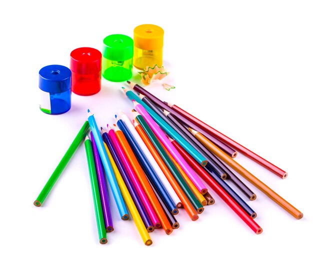 Sommige kleurpotloden van verschillende kleuren en puntenslijpers en potloodspaanders geïsoleerd