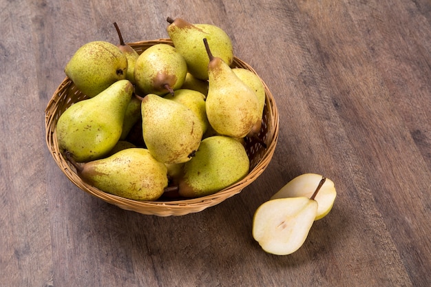 Sommige peren in een mand op een houten oppervlak. Vers fruit