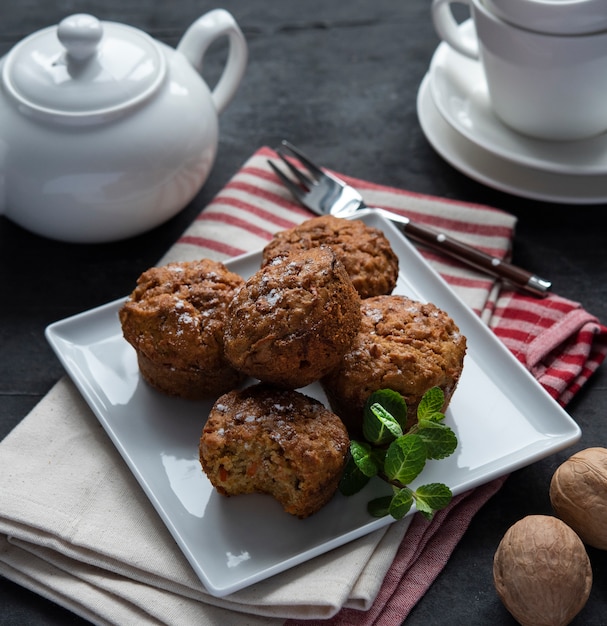 Sommige wortel muffins met noten en mint witte kopje thee ontbijt bakkerij