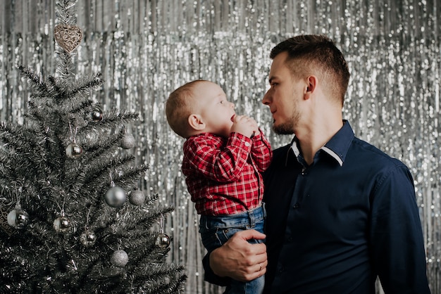 息子とパパ、クリスマスツリーで彼の父の腕の中で小さな男の子