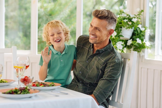 一緒に外で昼食を食べながら笑っている息子とパパ