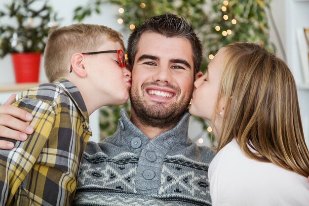 Son and daughter kissing father in the face