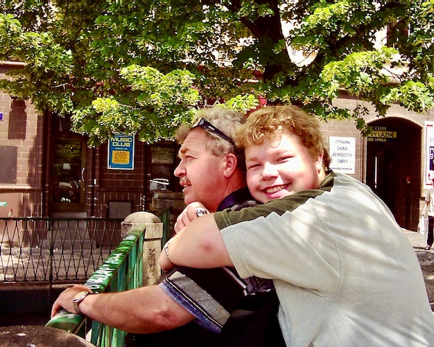 Photo son embracing father against trees