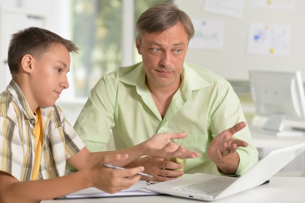 Son and father using laptop at home