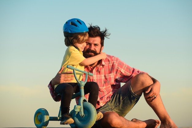 写真 息子が父父を抱き締めて子供が自転車に乗るのを手伝う