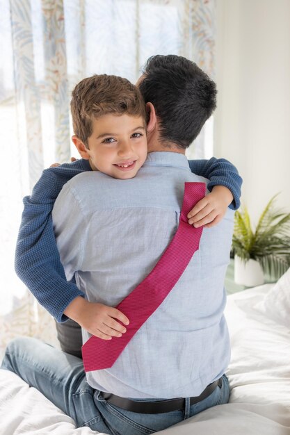 Photo son huging his father with a necktie on his hands