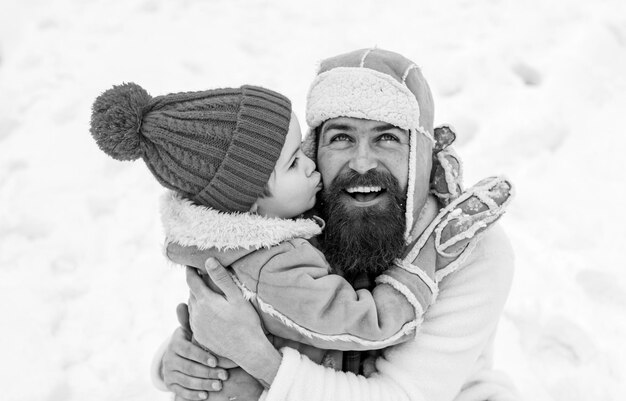 Son hugs his dad on winter holiday dad and baby son playing\
together outdoors happy child playing wi