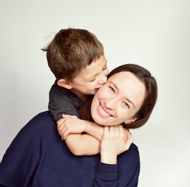 Son hugs mom on white