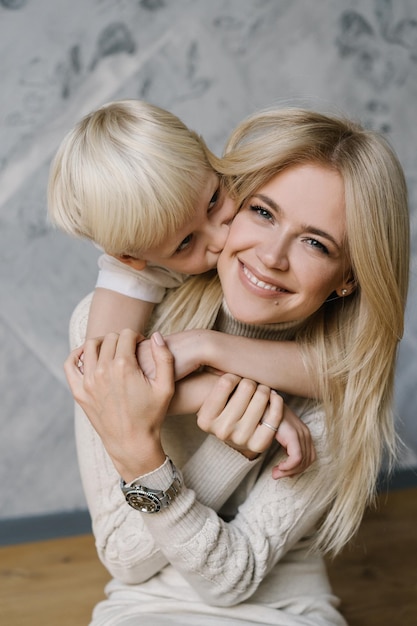 Son kissing mother on cheek while embracing at home