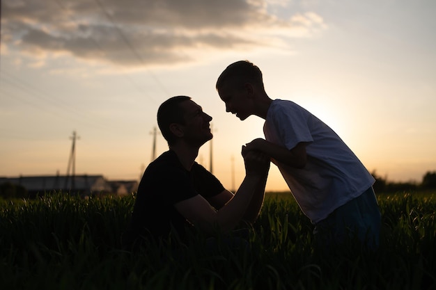 The son leaned towards his father in the background light