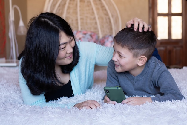 Il figlio e la mamma di aspetto asiatico trascorrono del tempo divertente insieme a guardare video su internet