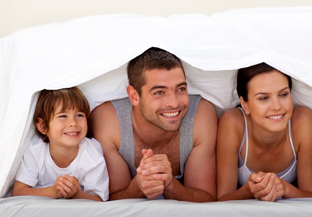 Son and parents playing under the bedsheets