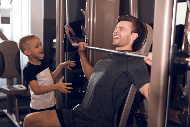 Son Support To Father While Lifting The Barbell