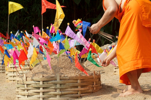 Songkran-festival, Boeddhistische monnik maakt zandchedi en speldt traditionele vlaggen, Chiangmai, Thailand.