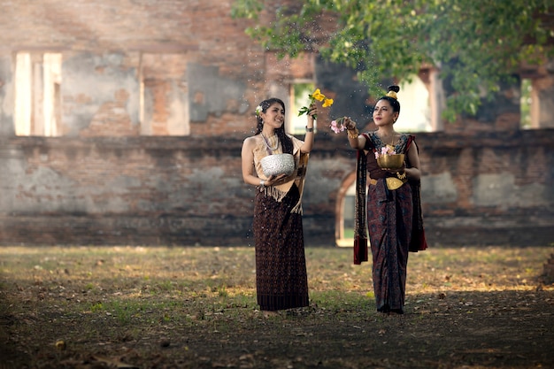 写真 ソンクラン祭り。タイの民族衣装を着た少女がソンクランの日に水をはねかけています。