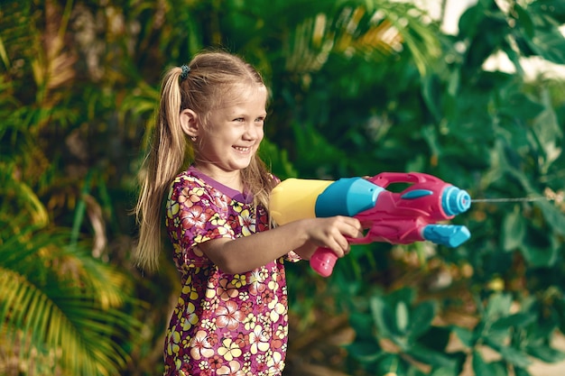 ソンクランの休日プラスチック色の水鉄砲で面白い女の子のアロハシャツ。タイの休日。タイの新年