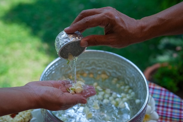 ソンクランまたはタイの新年祭タイの伝統的な尊敬する長老たちの手に水を注ぐ