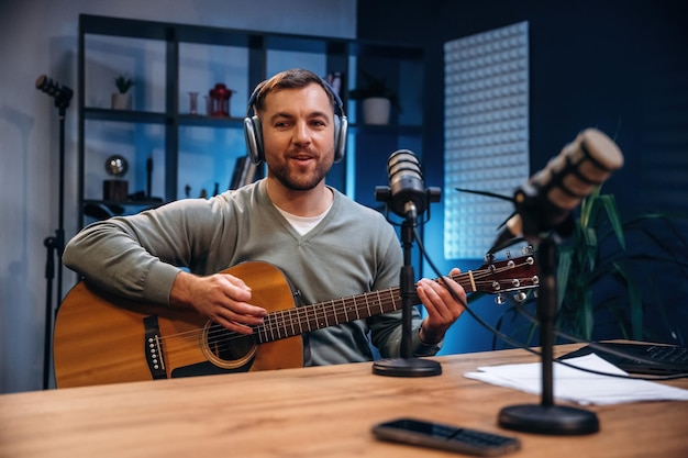 Songwriter met akoestische gitaar Man met microfoon in de studio conceptie van podcast
