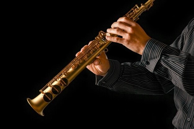 Soprano saxophone in hands on a black surface