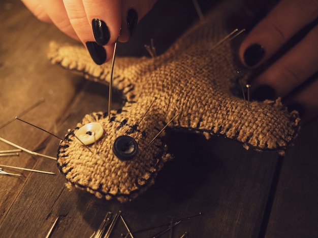 A sorceress pierces a voodoo doll with a pin, causing harm or damage to a person, closeup