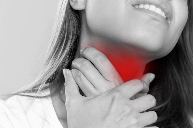 喉の痛み首を抱えた喉の痛みを伴う若い女性のクロップド白黒ショット