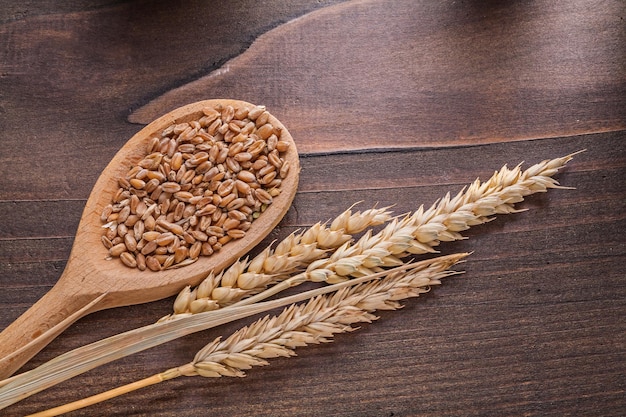 Sorns in wooden spoon and ears of wheat on old board food and drink concept