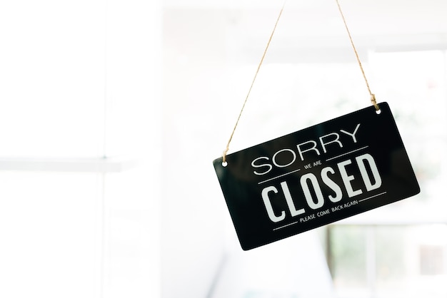 Sorry and Closed sign board through the glass of door in the cafe with clear interior white