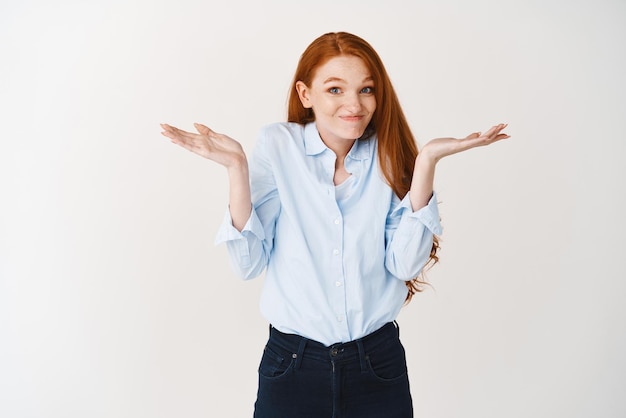 Sorry I dont know Clueless redhead girl shrugging shoulders and smiling standing over white background