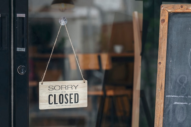 Photo sorry we're closed sign board hanging on a dirty glass door.