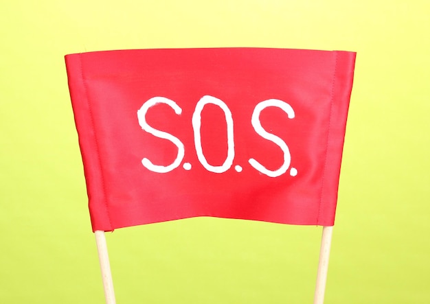 SOS signal written on red cloth on green background