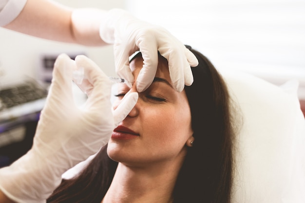 Сosmetologist doctor injects botox into the patient's forehead