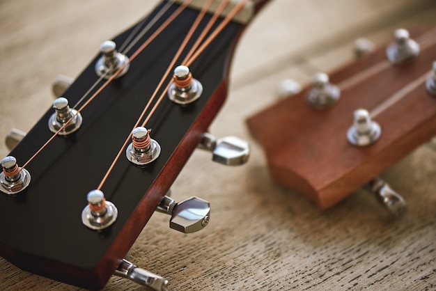 Sound adjusting. Close up photo of guitar necks with tuning keys for adjusting strings against wooden background. . Music equipment. Musical instruments. Music concept