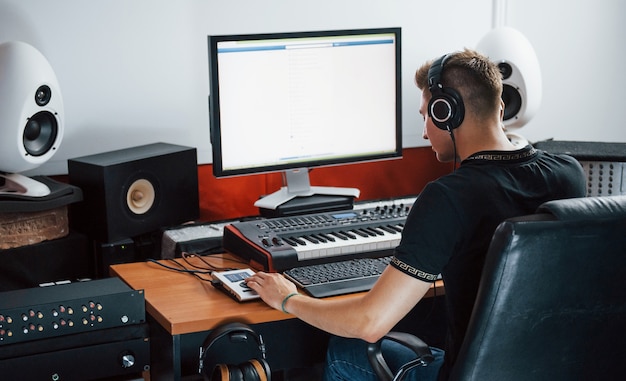 Sound engineer in headphones working and mixing music indoors in the studio.