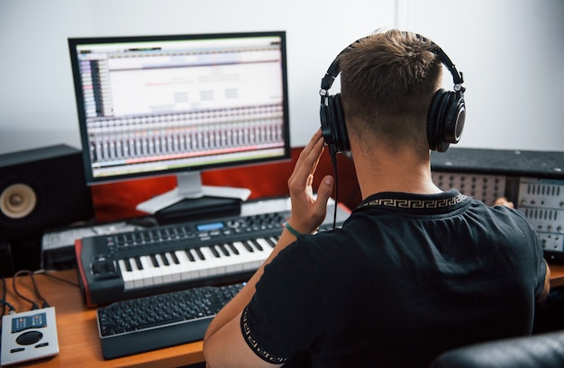 Photo sound engineer in headphones working and mixing music indoors in the studio.