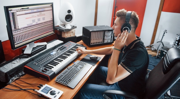 Sound engineer in headphones working and mixing music indoors in the studio.