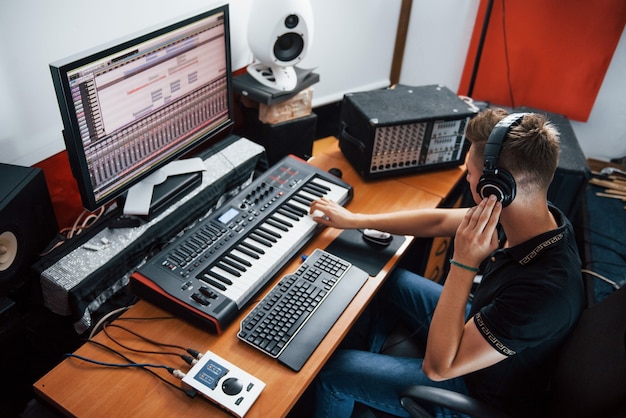 Sound engineer in headphones working and mixing music indoors in the studio.