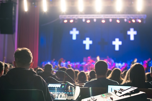 Photo soundman working on the mixing console in concert hall