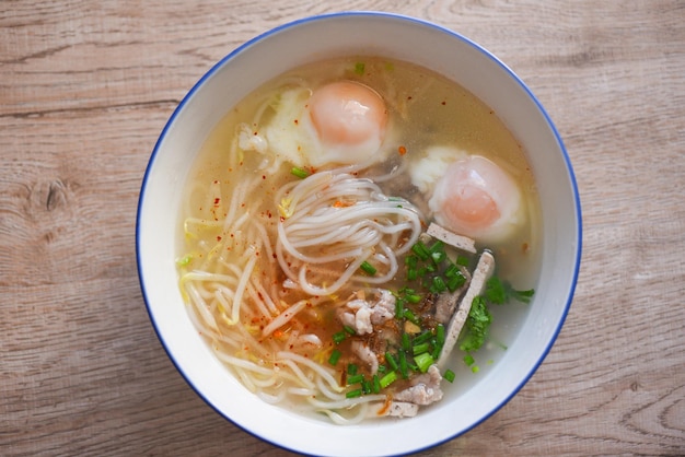 수프 그릇, 베트남 돼지고기 부드러운 삶은 계란, 콩나물 야채 봄 양파를 넣은 수프 국수 돼지고기 흰 국수, 나무 탁자에 있는 수프 그릇, 태국 아시아 음식