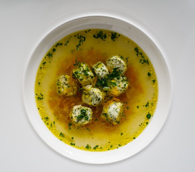 Soup broth with meatballs in a white plate. Concept for a menu in a restaurant