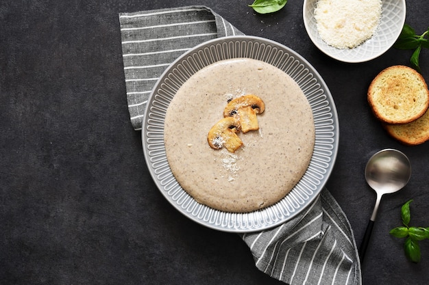 Soup puree with mushrooms and cheese on a concrete background.