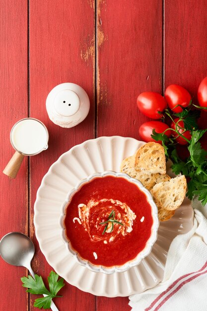 Soup Tomato cream soup or gazpacho with herbs seasonings cherry tomato and parsley in white bowl on old red wooden background Healthy vegetable soup Spanish cold soup Top view with copy space