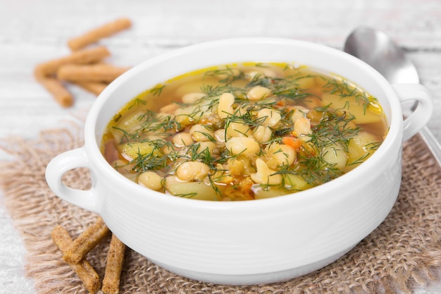 Soup with beans with dill in white ceramic bowl