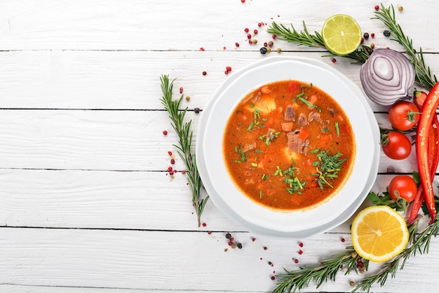 Zuppa con pomodori di manzo e verdure fresche su uno sfondo di legno vista dall'alto copia spazio