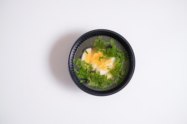 Zuppa con uova in una ciotola usa e getta consegna del cibo