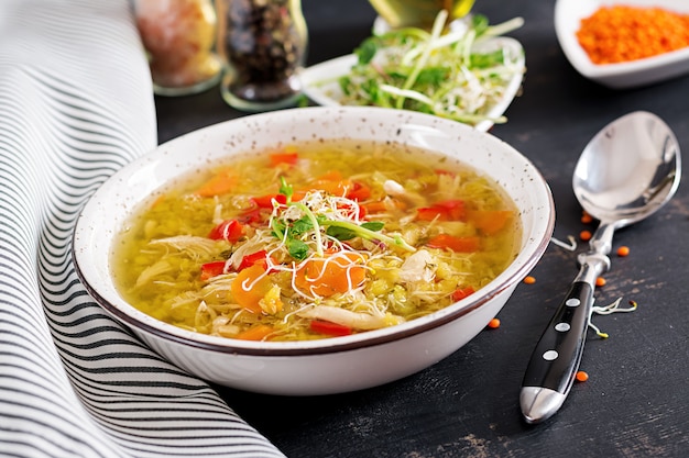 Soup with lentils, carrots, chicken meat, paprika, celery in a bowl.