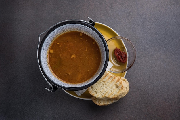 Soup with meat and vegetables in a pot on a dark background
