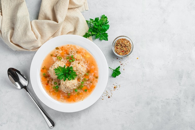 Soup with meatballs and rice on a gray background with dill and spices. Top view. Healthy food.